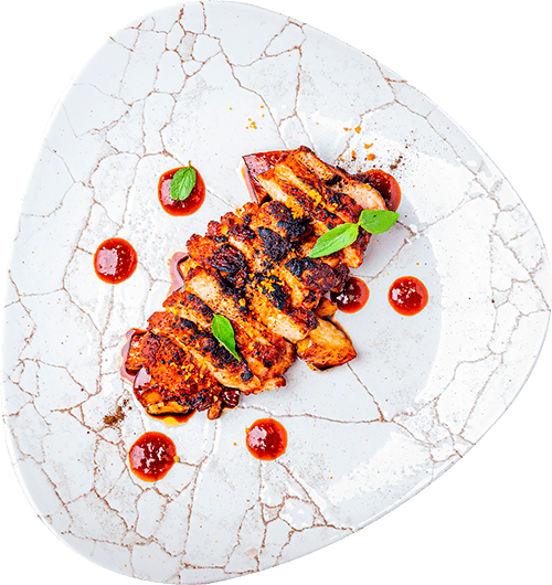 Un plato de carne asada en rodajas aderezada con hierbas y salsa sobre un plato blanco de textura agrietada, que presenta una fusión de sabores que elevan su arte culinario.